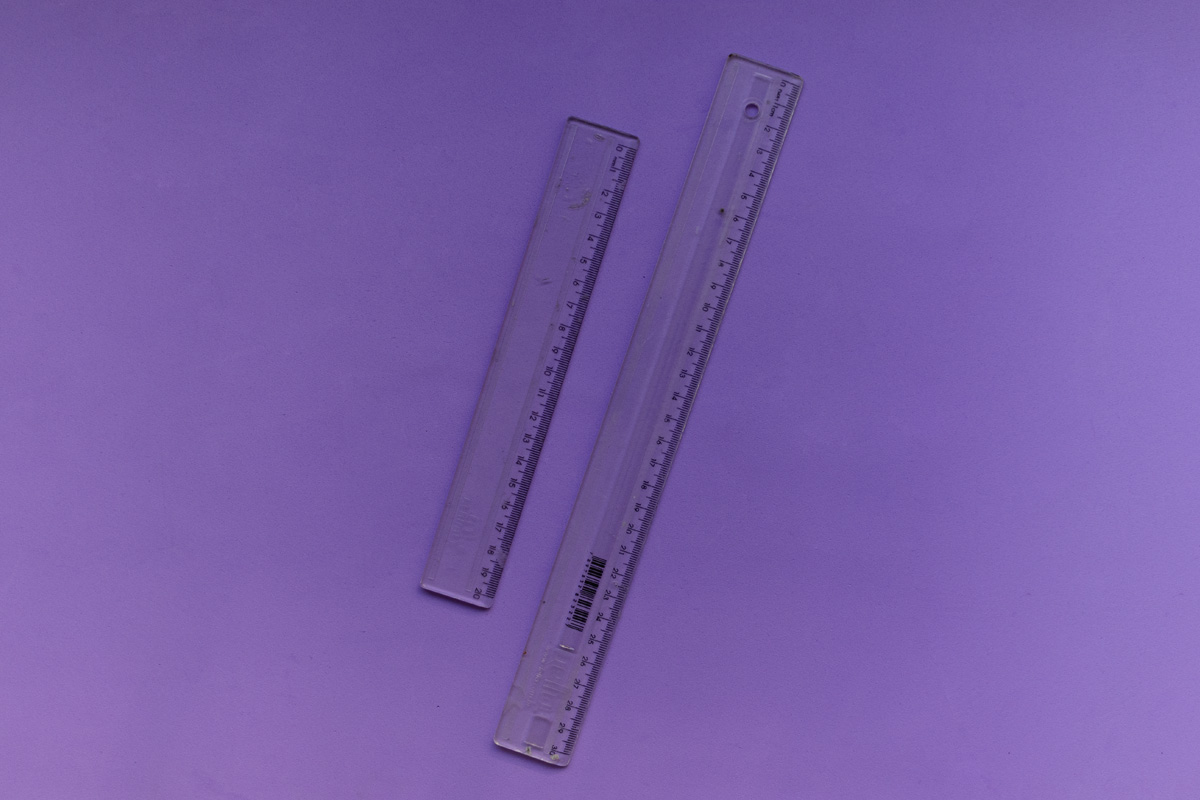 Two transparent rulers sitting on a purple background.