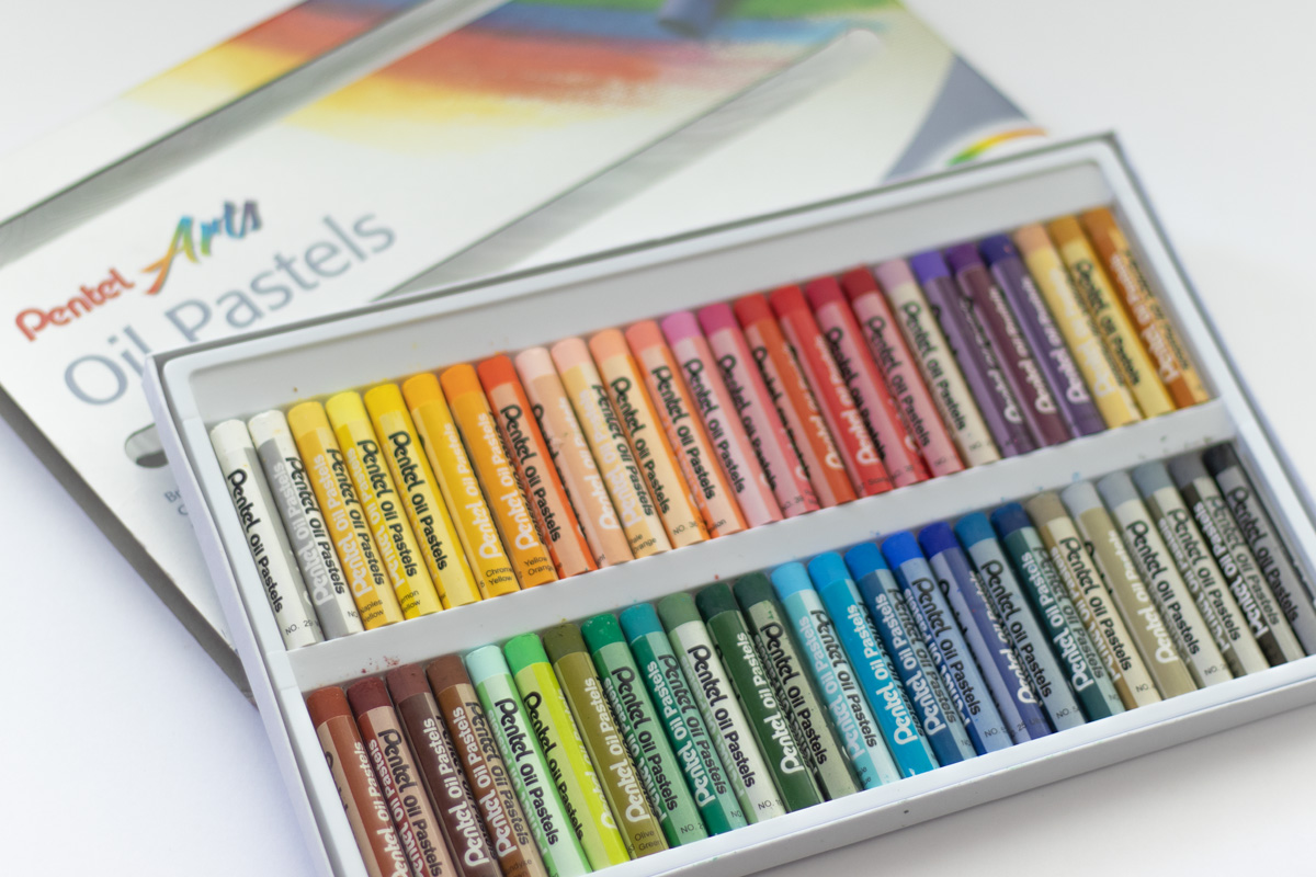 A bunch of new colorful oiil pastels sitting on a desk.