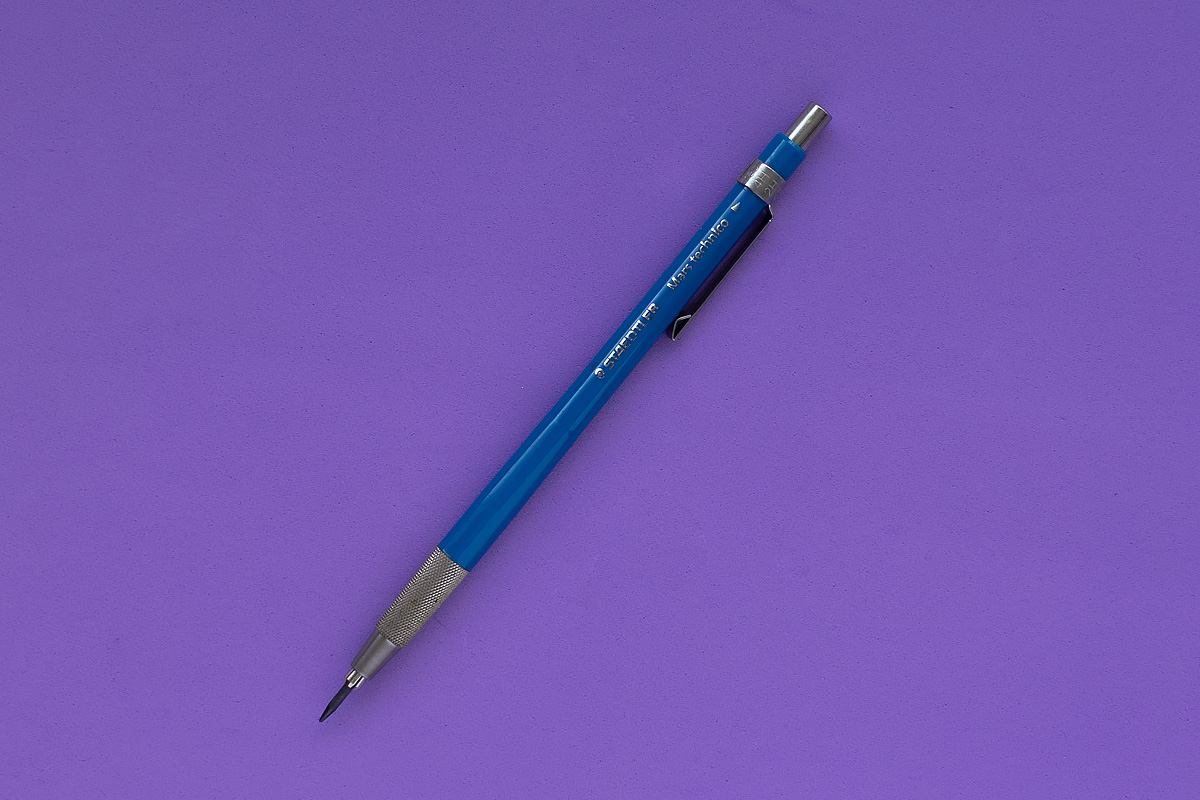 A blue Staedtler Mars Technico pencil standing on a purple background.