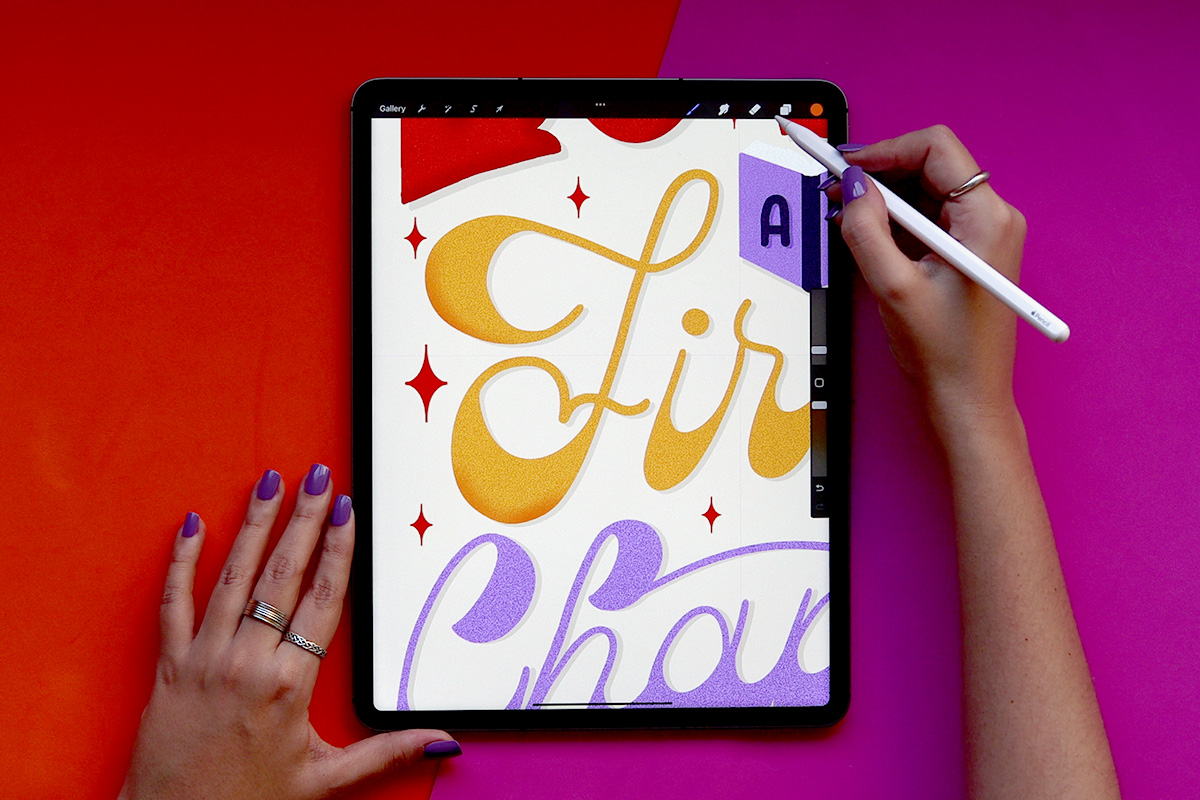 iPad screen with two hands, one holding an Apple Pencil while drawing some lettering.