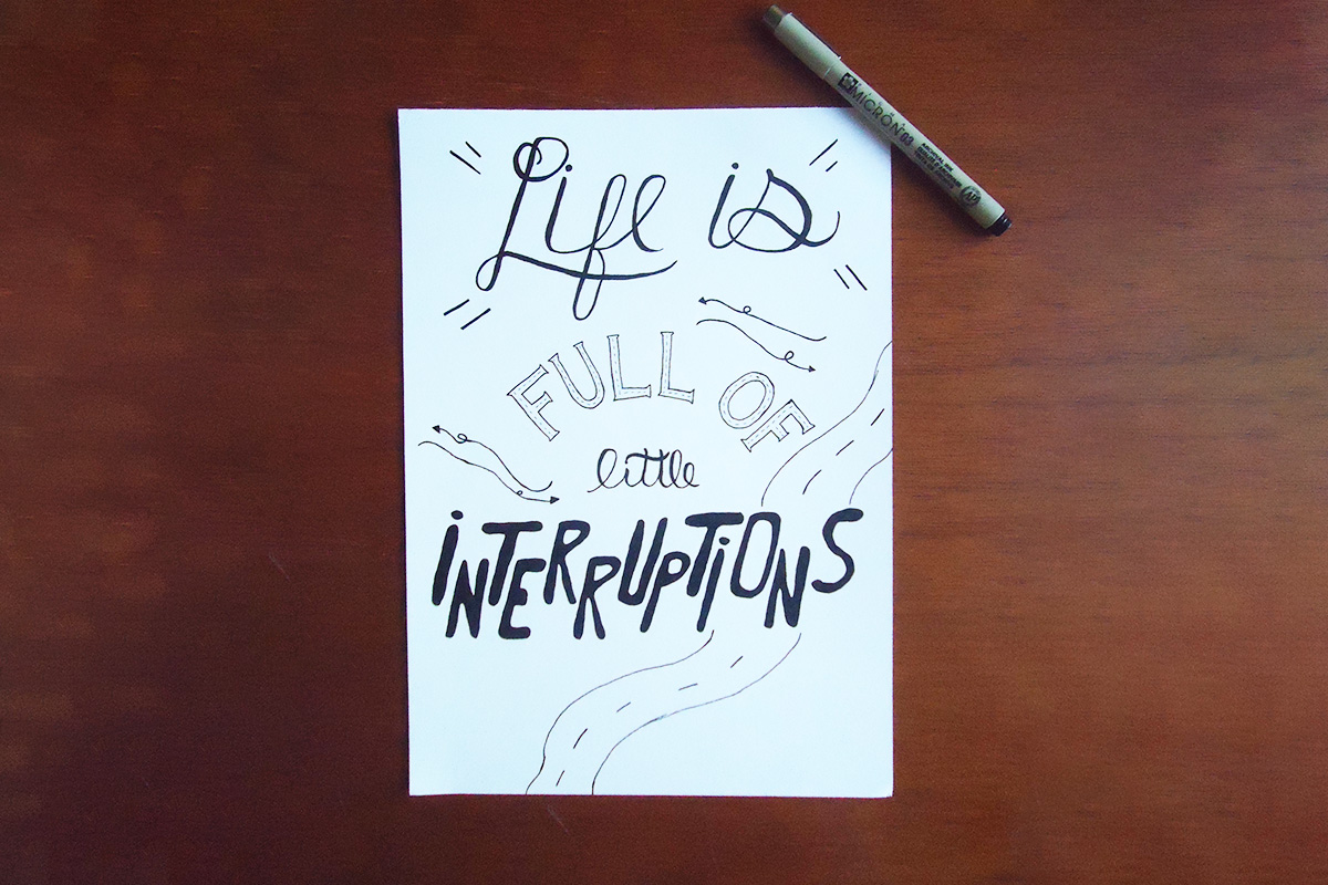 A piece of paper with lettering that reads "Life is full of little interruptions"